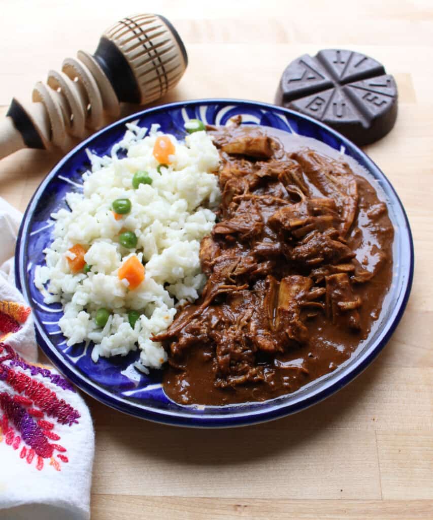 Mole de pavo servido junto a arroz blanco en un plato azul.