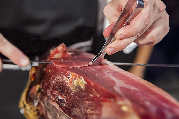 Imagen de alguien cortando finamente las piernas de prosciutto.