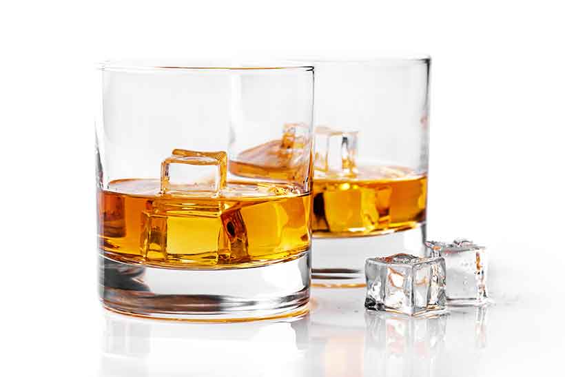 Dos vasos de whisky uno al lado del otro, llenos de cubitos de hielo.