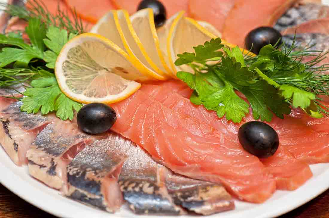 Salmón crudo fresco con rodajas de limón y decoración de hojas.