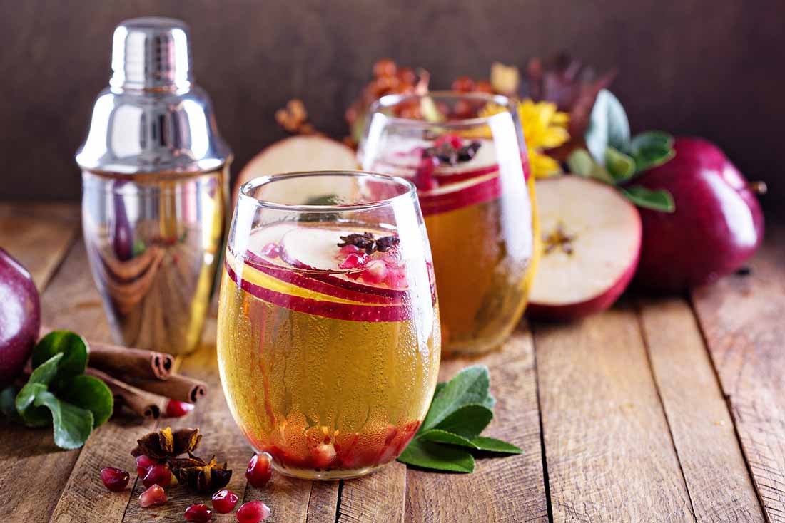 Dos vasos de sidra junto a manzanas en Superficie de madera.