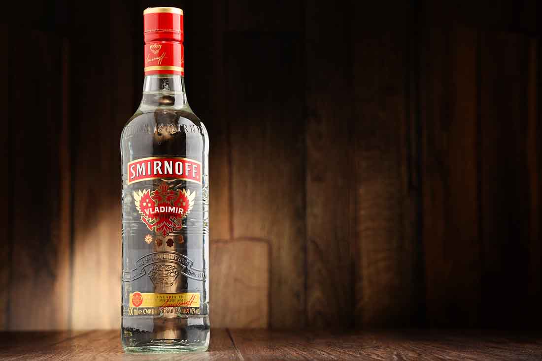 Botella de vidrio de Smirnoff Vodka sobre una superficie de madera.