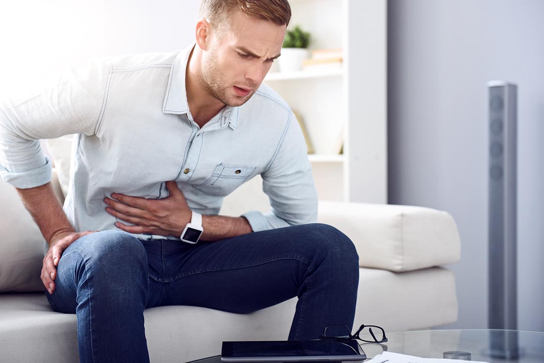 Hombre Que Sufre Abdominal - Sosteniendo El Abdomen Con La Mano Izquierda.