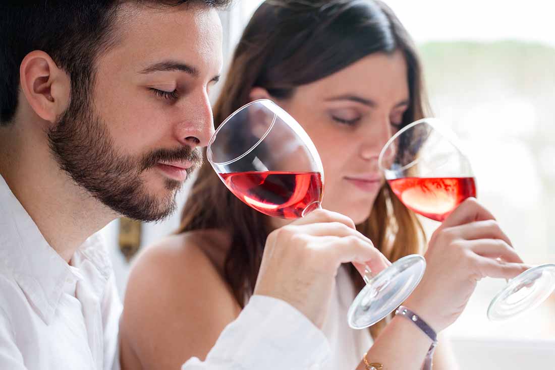 Pareja joven bebiendo una copa de vino rosado.