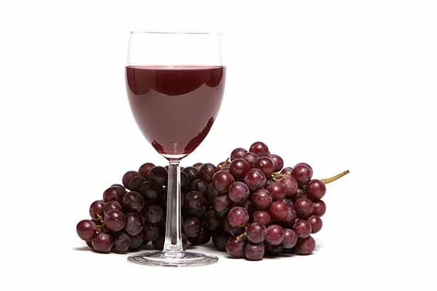 Copa de vino tinto cerca del racimo de uvas.