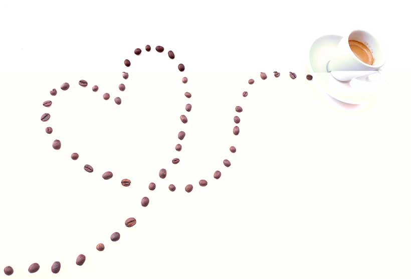 Imagen de taza de café con granos de café haciendo forma de corazón.