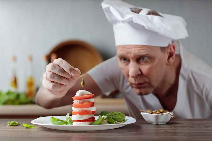 Chef Decorando Ensalada Con Alcaparras Y Mozzarella.