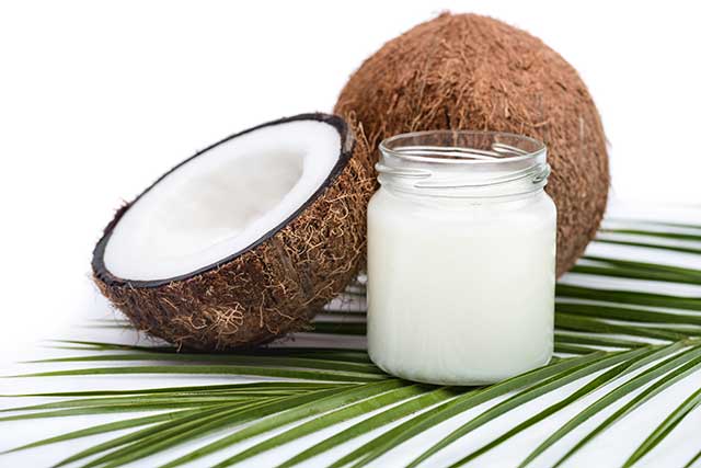 Tarro de aceite de coco junto a la mitad de coco.