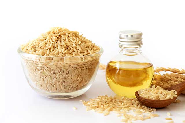 Aceite de salvado de arroz junto al cuenco de arroz integral.