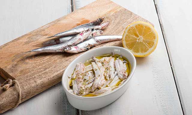 Anchoas Enteras Y Filetes De Anchoa Marinados En El Tazón De Fuente Blanco.